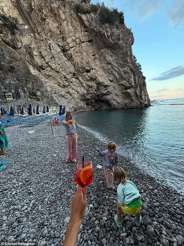 Druga je bila od nje kako drži čašu aperola spritza svojoj prijateljici u pješačkoj udaljenosti dok su se nazdravljali jedni drugima pored svojih sinova igrajući