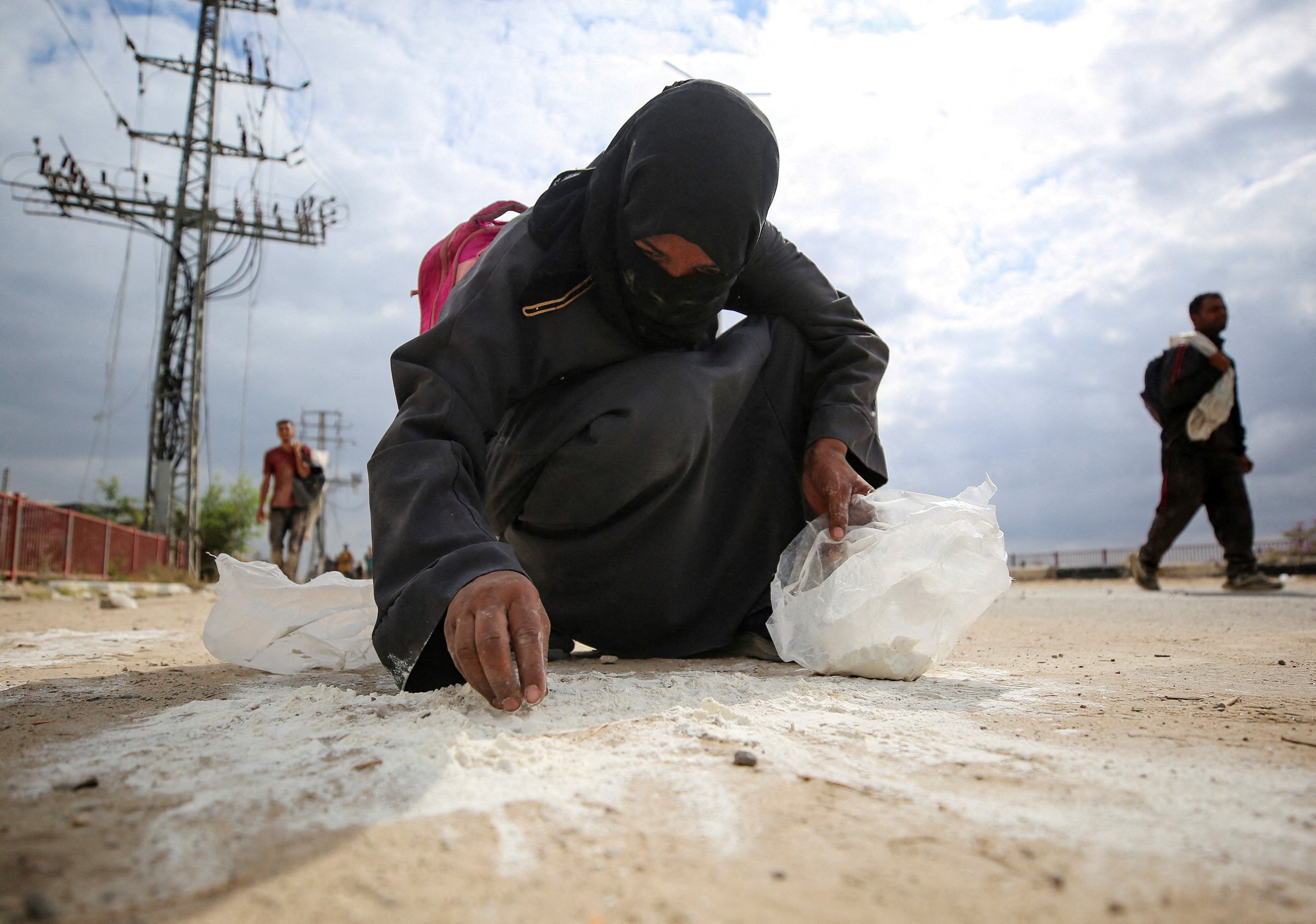 Žena sakuplja brašno s zemlje dok Palestinci dobivaju zalihe za pomoć iz američke humanitarne zaklade Gaze (GHF)