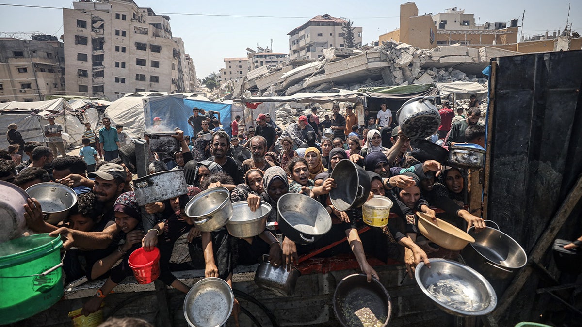 Palestinci koji nose tave, okupljaju se da bi primili tople obroke, 23. srpnja 2025. godine.