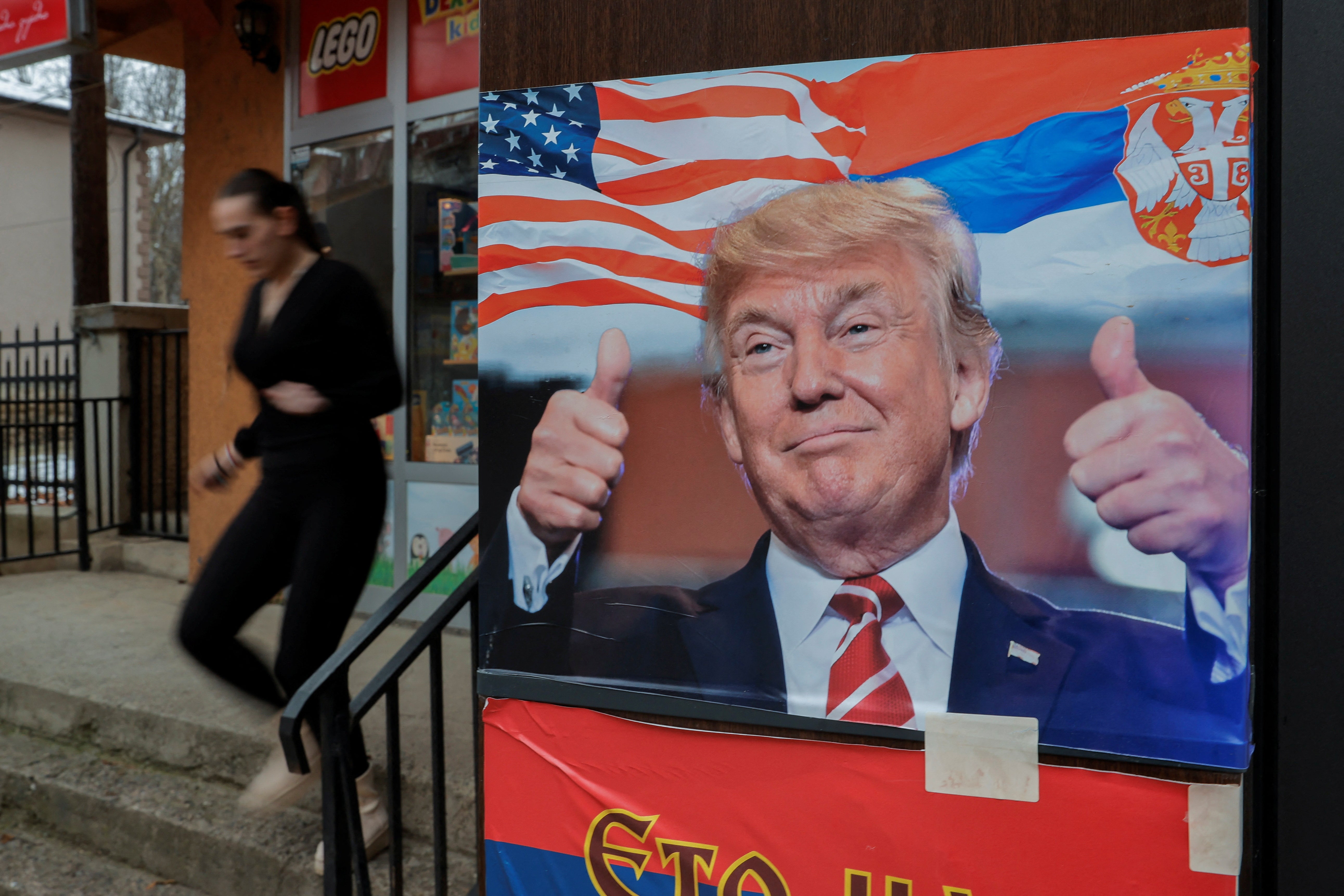 Žena hoda blizu plakata koji prikazuje Trumpa sa srpskom zastavom, u Mitrovici, Kosovo u siječnju