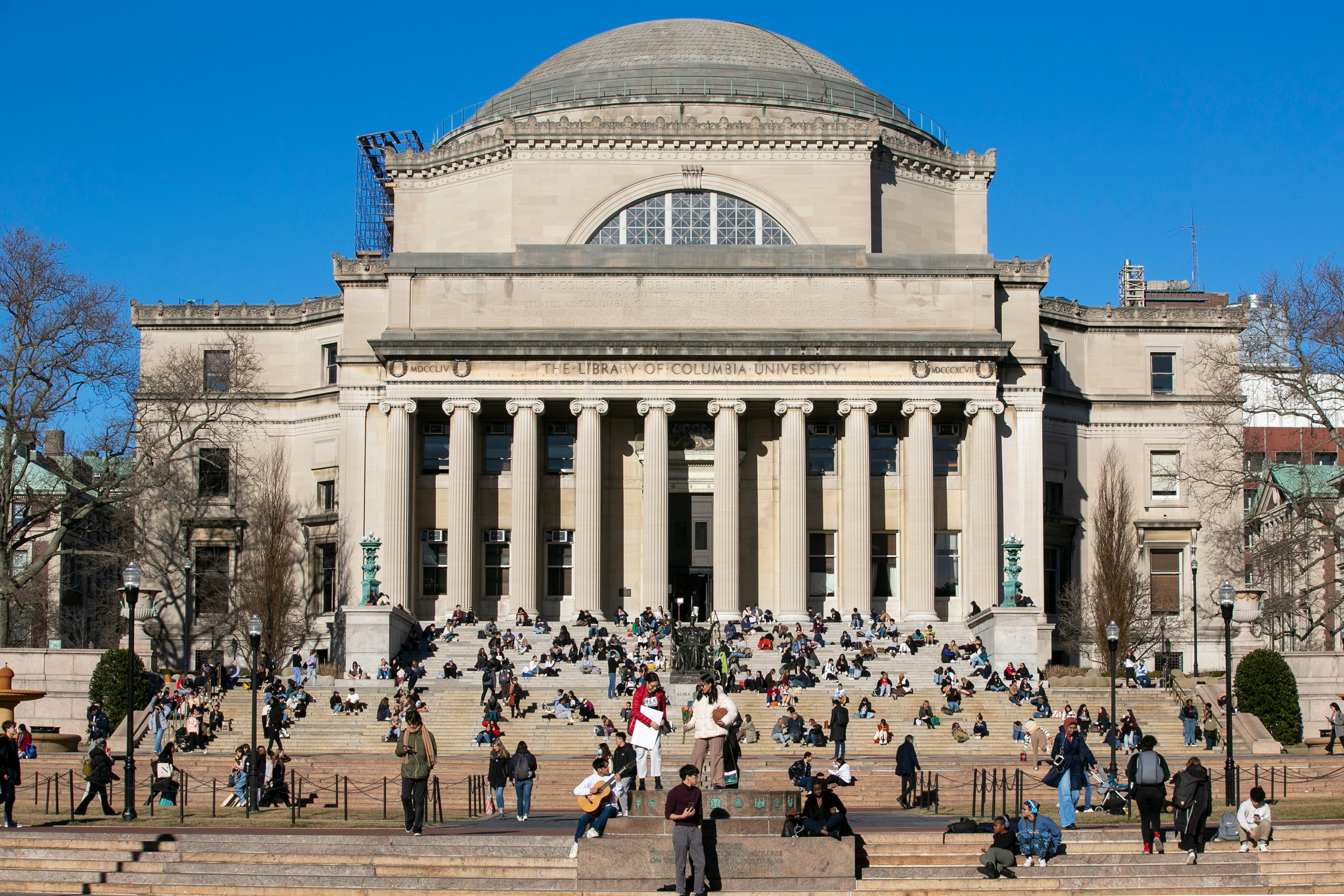Studenti sjede na prednjim stepenicama niske Memorijalne knjižnice u kampusu Sveučilišta Columbia u New Yorku. Columbia Sportska odjeća tuži sveučilište zbog navodnog kršenja ugovora i kršenja autorskih prava