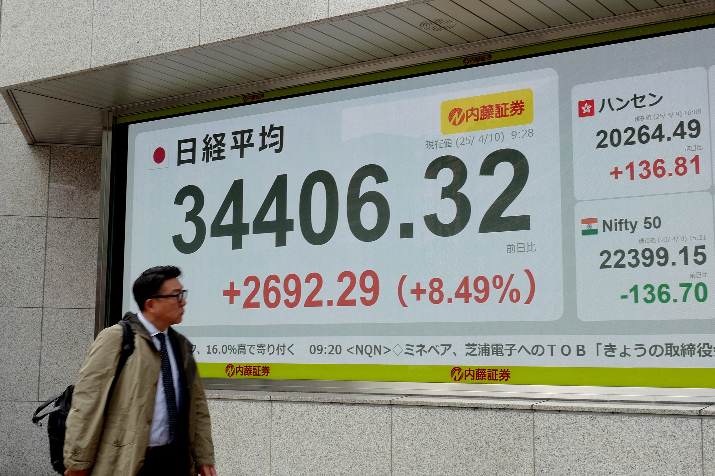 Čovjek gleda na elektroničku ploču koja pokazuje broj nikkeija prosjeka dionica na Tokijskoj burzi u Japanu