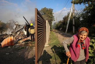 Stanovnik hoda ulicom dok vatrogasac radi na mjestu ruskog raketnog štrajka, usred ruskog napada na Ukrajinu, u selu Sknyliv na periferiji Lviva