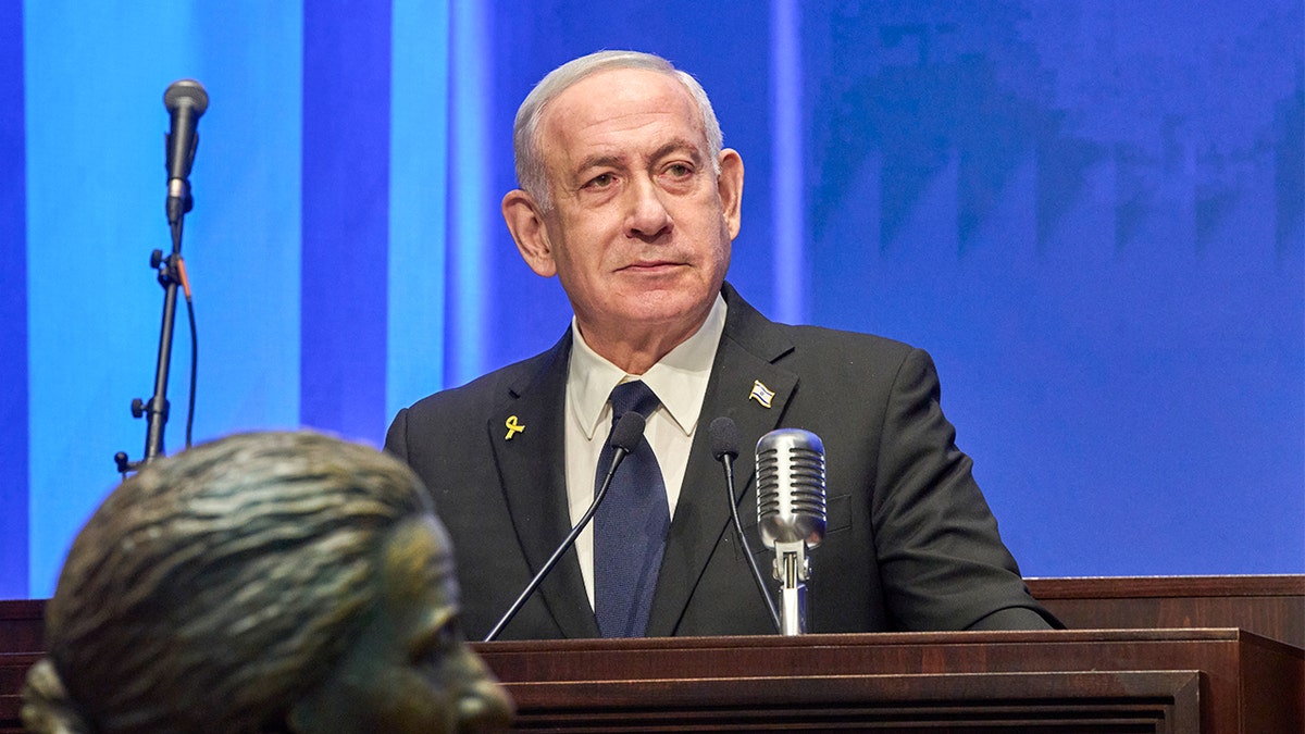 Izraelski premijer Benjamin Netanyahu stoji na postolju, govoreći u mikrofonu