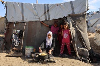 Palestinka kuha pored djece ispred šatora u kampu za raseljene ljude u Khan Yunisu u južnoj Gazi Strip, 29. rujna 2025.