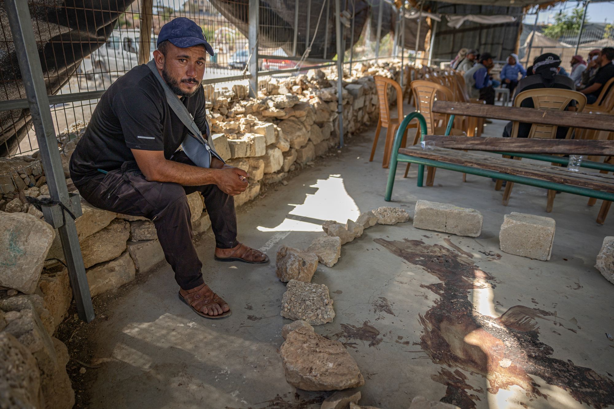Awdah's cousin Ahmed, injured from the attack, sits next to the dried pool of blood where his relative was shot dead by settlers in the West Bank