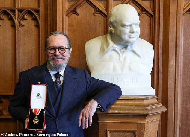 Glumac pokazuje svoju medalju za usluge drami, dok pozira uz poprsje bivšeg premijera Sir Winstona Churchilla