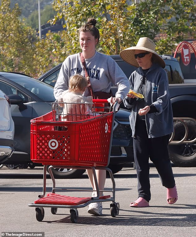 Manekenka 6ft2in imala je svoju brinetu kosu skupljenu u čvor s torbicom na križu dok je obuvala bijele tenisice