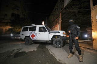 Puškarac koji nosi uniformu brigada Al-Qassam, vojno krilo Hamasa, stoji čuvara dok vozila Crvenog križa ulaze u skladište navodno kako bi prikupile lijesove koji sadrže tijela četiri umrla talaca