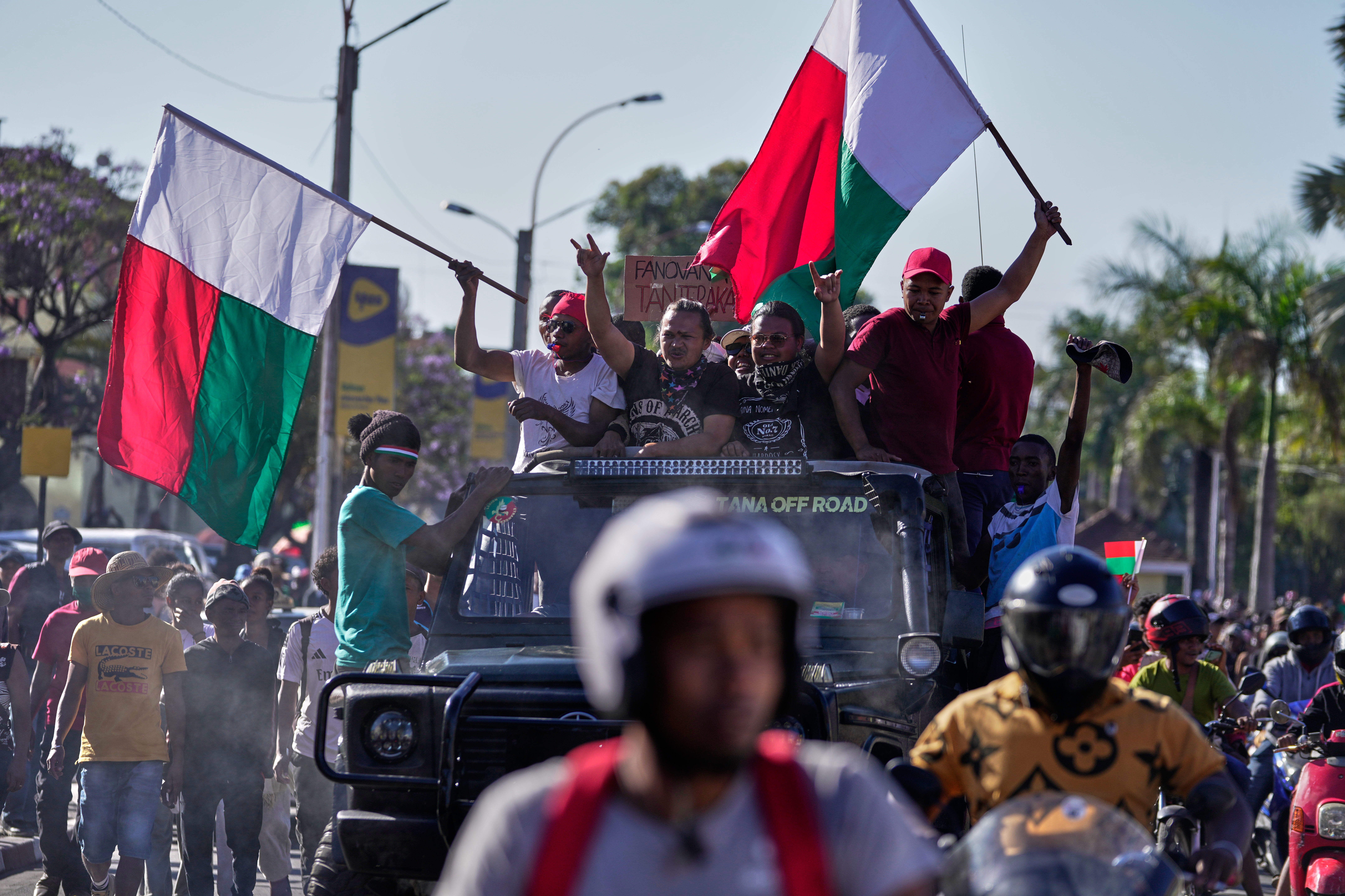 Prosvjednici plešu na vrhu automobila tijekom prosvjeda pozivajući predsjednika Andryja Rajoelinu da odstupi s vlasti u Antananarivu, Madagaskar, utorak, 14. listopada 2025. (AP Photo/Brian Inganga)
