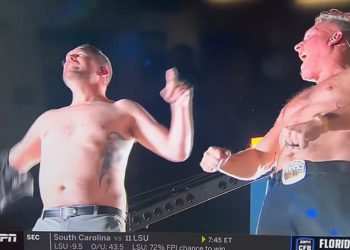 Navijači fakulteta zaprepašteni dok trener udara košulju kako bi otkrio dodirnu tetovažu na prsima