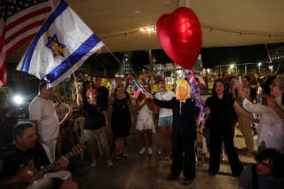 Nošenje maske koja prikazuje američkog predsjednika Donald Trump maše izraelskom zastavom s žutom vrpcom u središtu