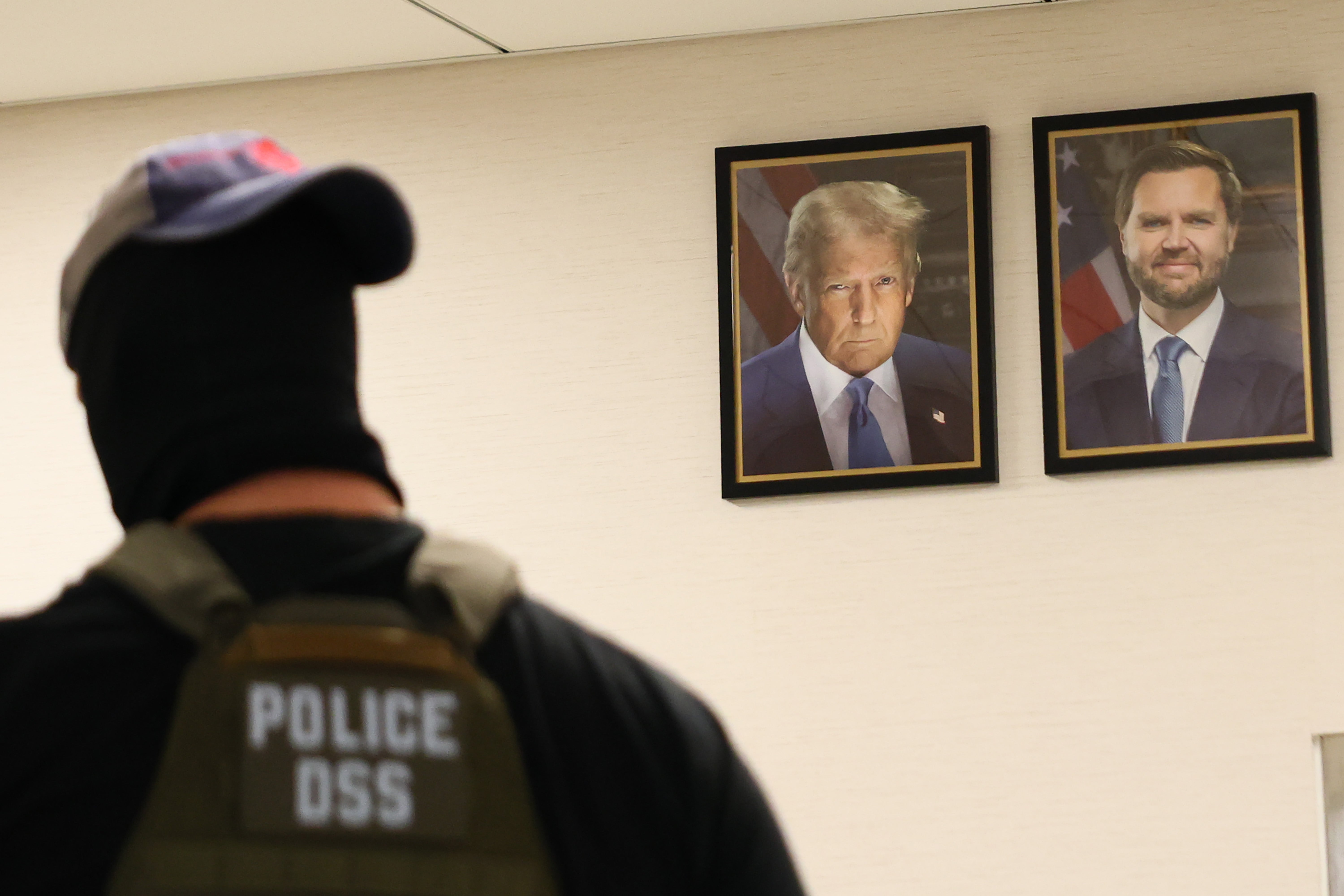 Federalni agent prolazi portreti američkog predsjednika Donalda Trumpa i američkog potpredsjednika JD Vancea dok patrolira dvorane savezne zgrade Ted Weiss u New Yorku 4. kolovoza 2025.