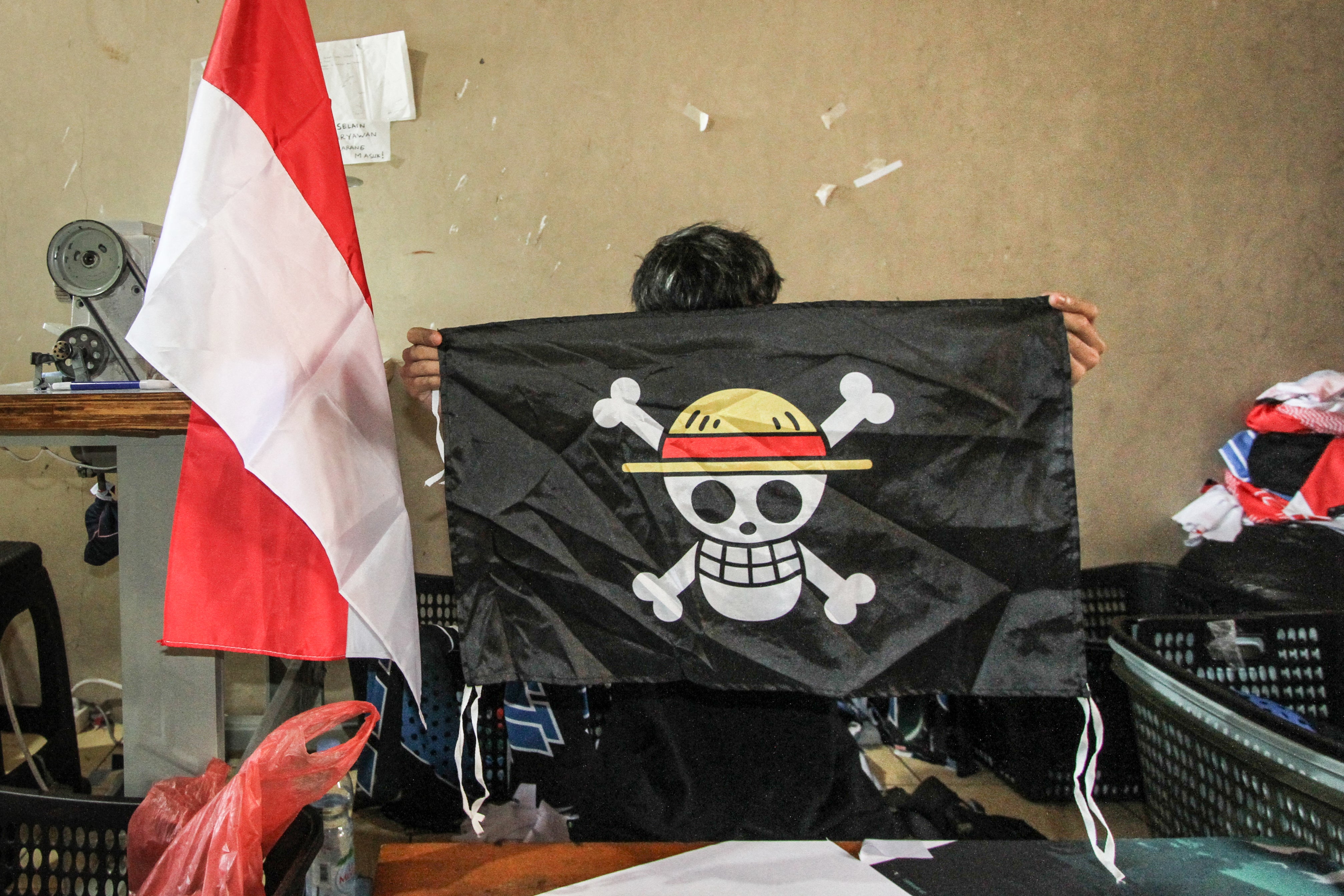Radnik drži repliku piratske zastave iz japanskog animea 'One Piece', napravljenu za prodaju dok neki Indonežani usvajaju simbol iz priče o otporu korumpiranoj svjetskoj vladi kako bi izrazili frustraciju vlastitom, na radionici majica u Karanganyaru, središnja Java, 6. kolovoza 2025.