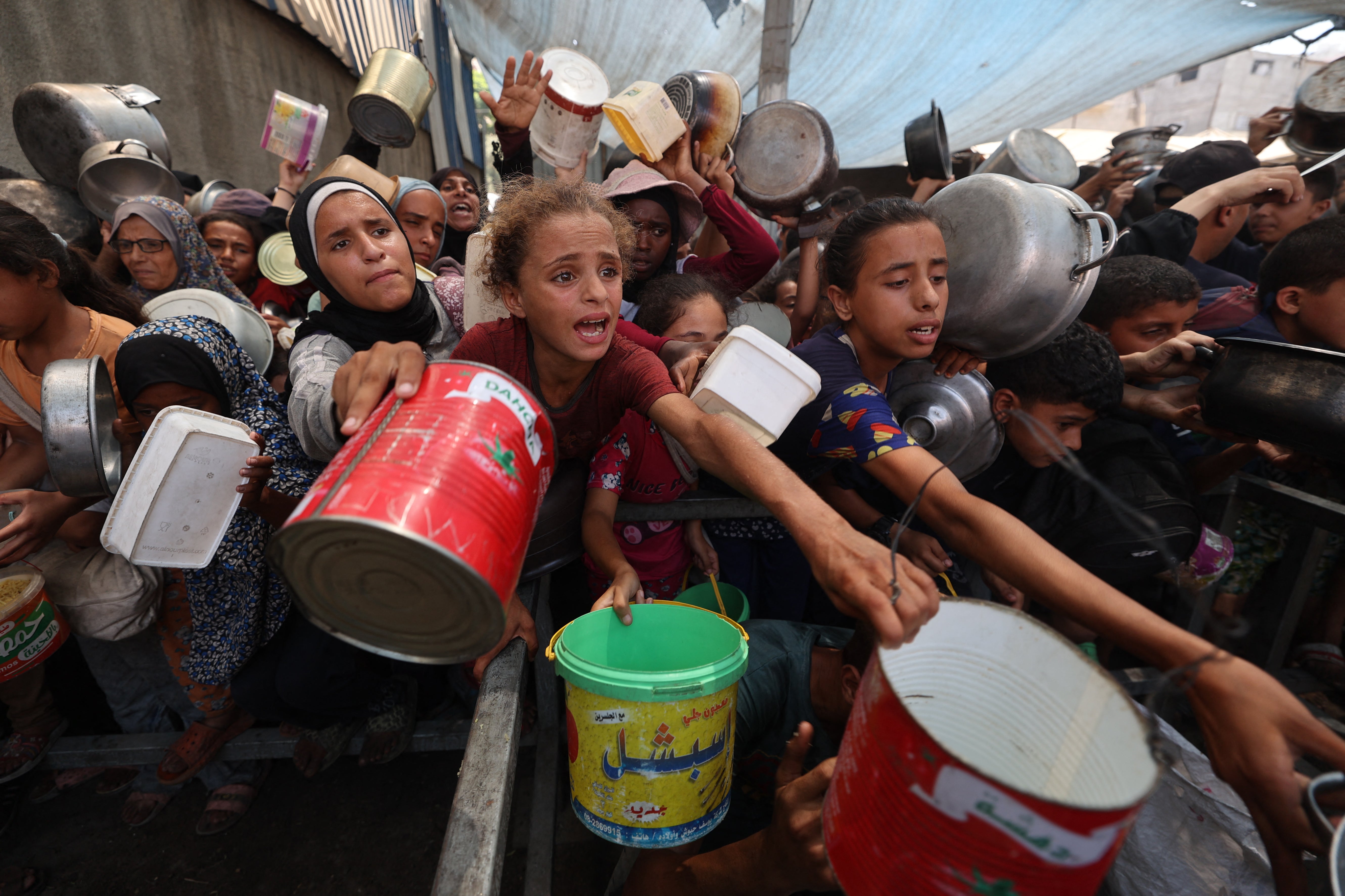 Palestinci se okupljaju kako bi primili kuhane obroke iz centra za distribuciju hrane u izbjegličkom kampu Nuseirat u središnjoj traci Gaze