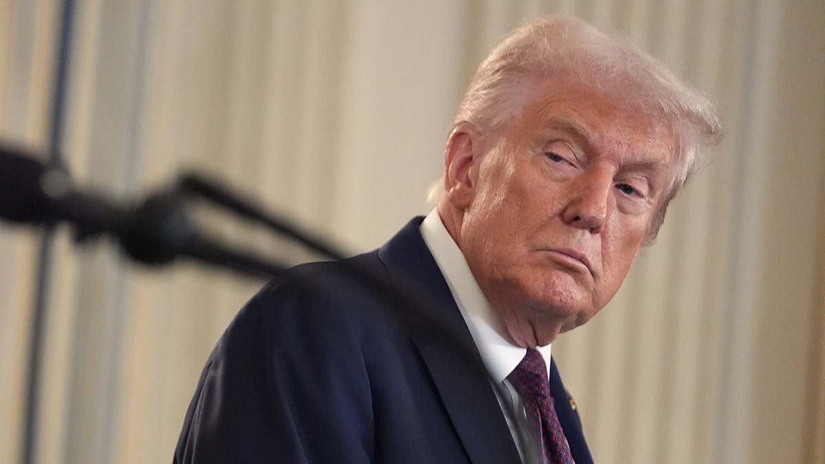 Donald Trump nosi tamno odijelo okreće glavu za slušanje tijekom konferencije za novinare