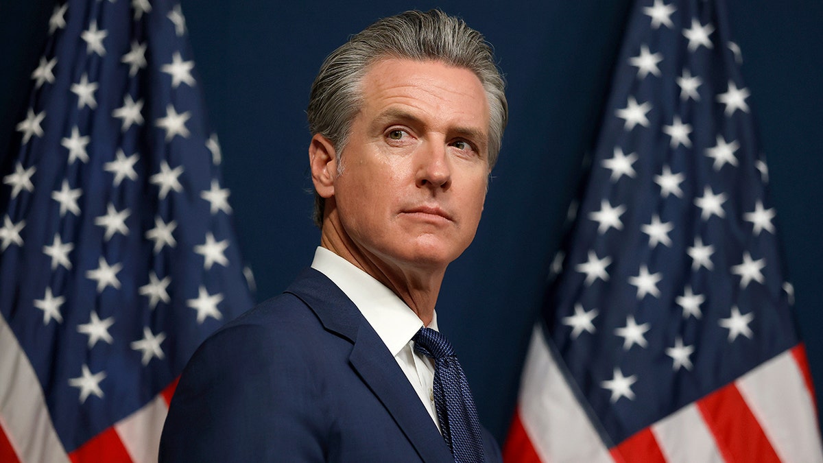 Kalifornijska vlada Gavin Newsom s dvije američke zastave u pozadini.