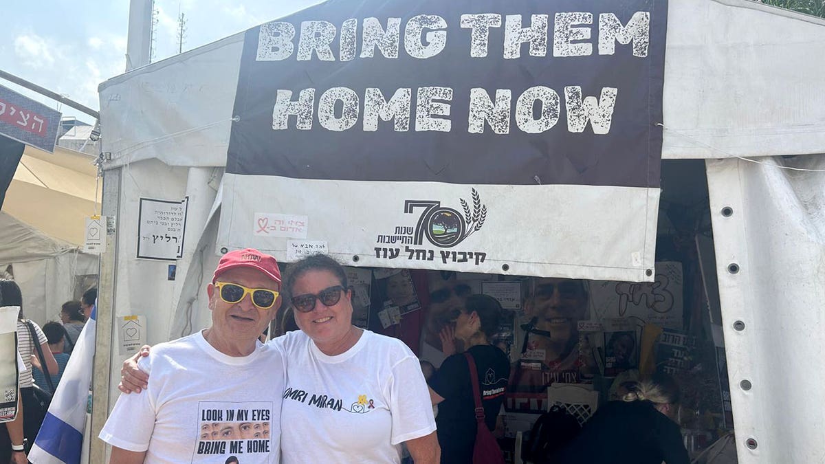 Muškarac i žena stoje nasmiješeni vanjski šator sa 