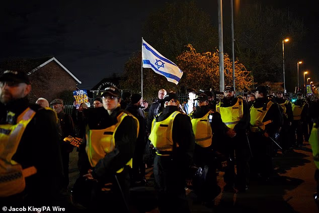 A pro-Israel fan holding a flag is escorted through the streets by a cordon of officers
