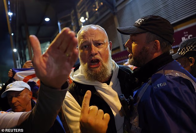 A supporter is held back by police as he shouts at another set of fans at Villa Park