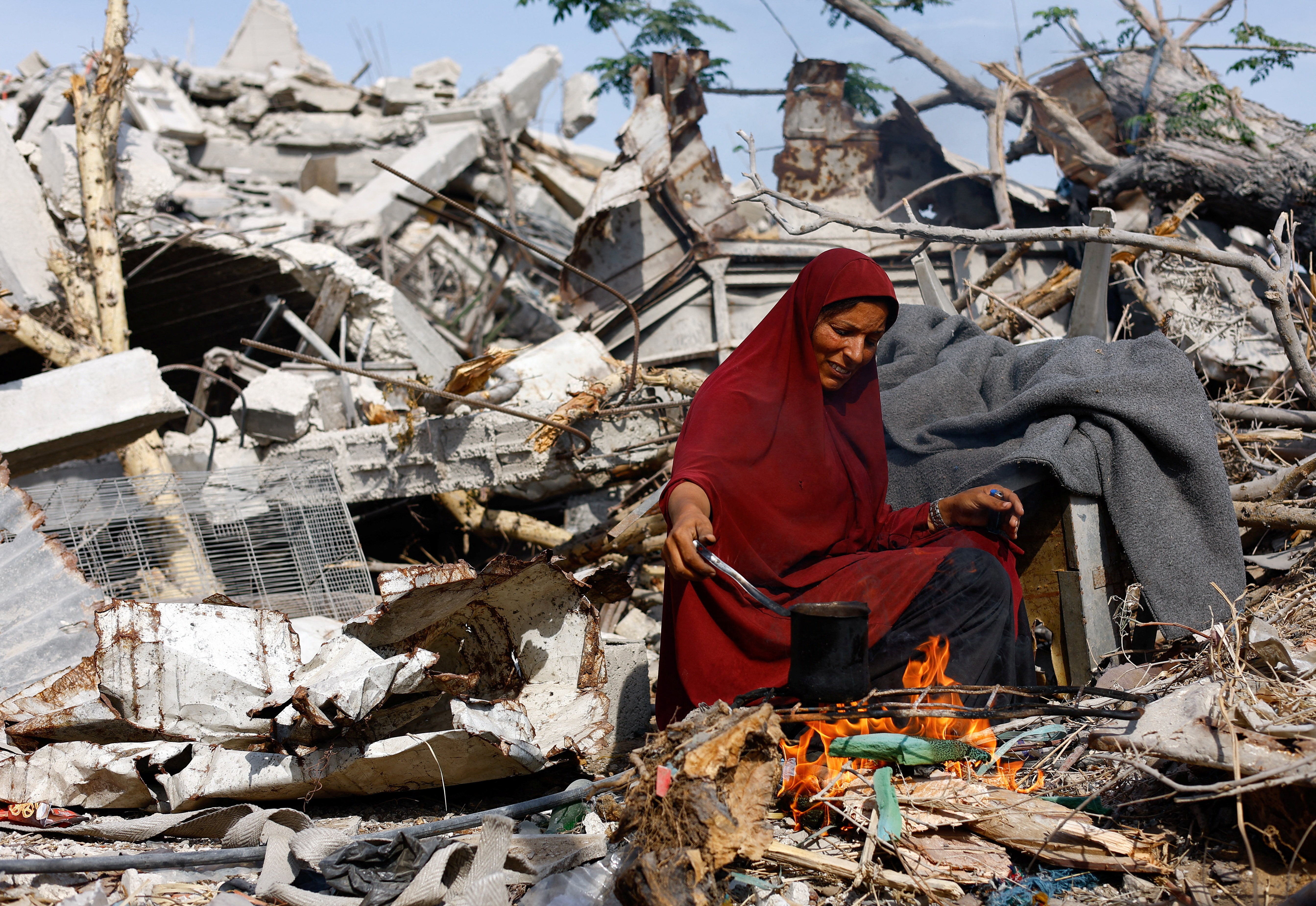 Palestinka kuha na vatri okružena ruševinama zgrada koje su uništile izraelske snage u gradu Gazi