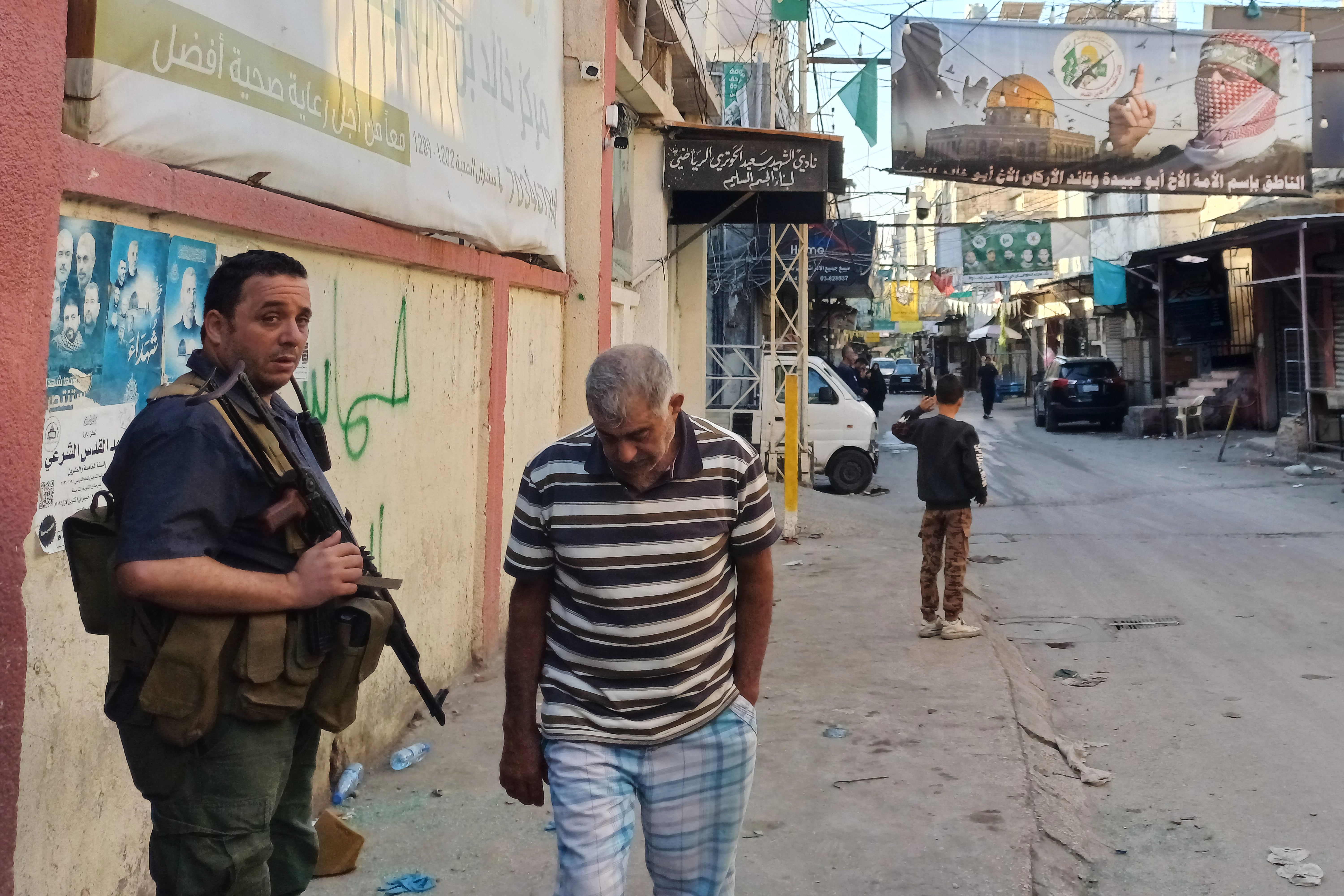 Naoružani napadač Hamasa, lijevo, čuva stražu blizu mjesta gdje je izraelski napad pogodio palestinski izbjeglički kamp Ain al-Hilweh u južnom Libanonu