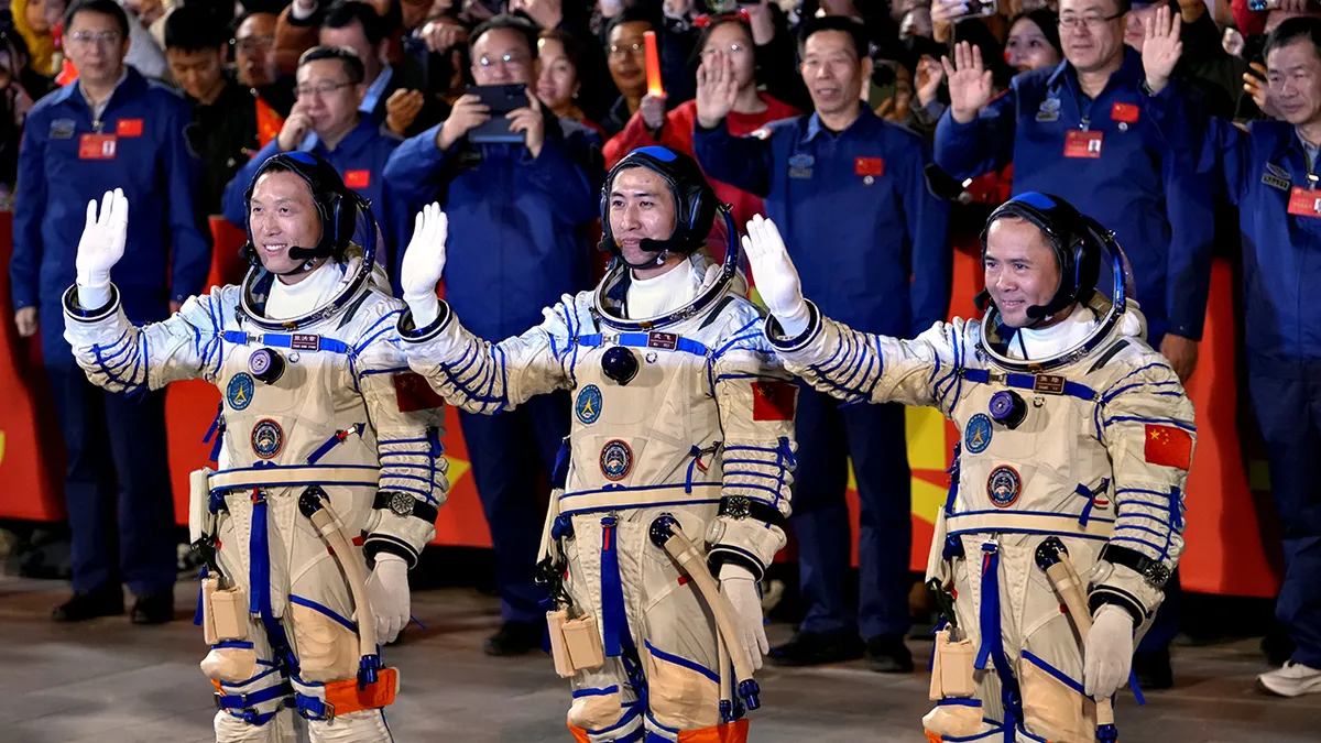 Kineski astronaut za misiju Shenzhou-21 stoji i maše u svemirskim odijelima