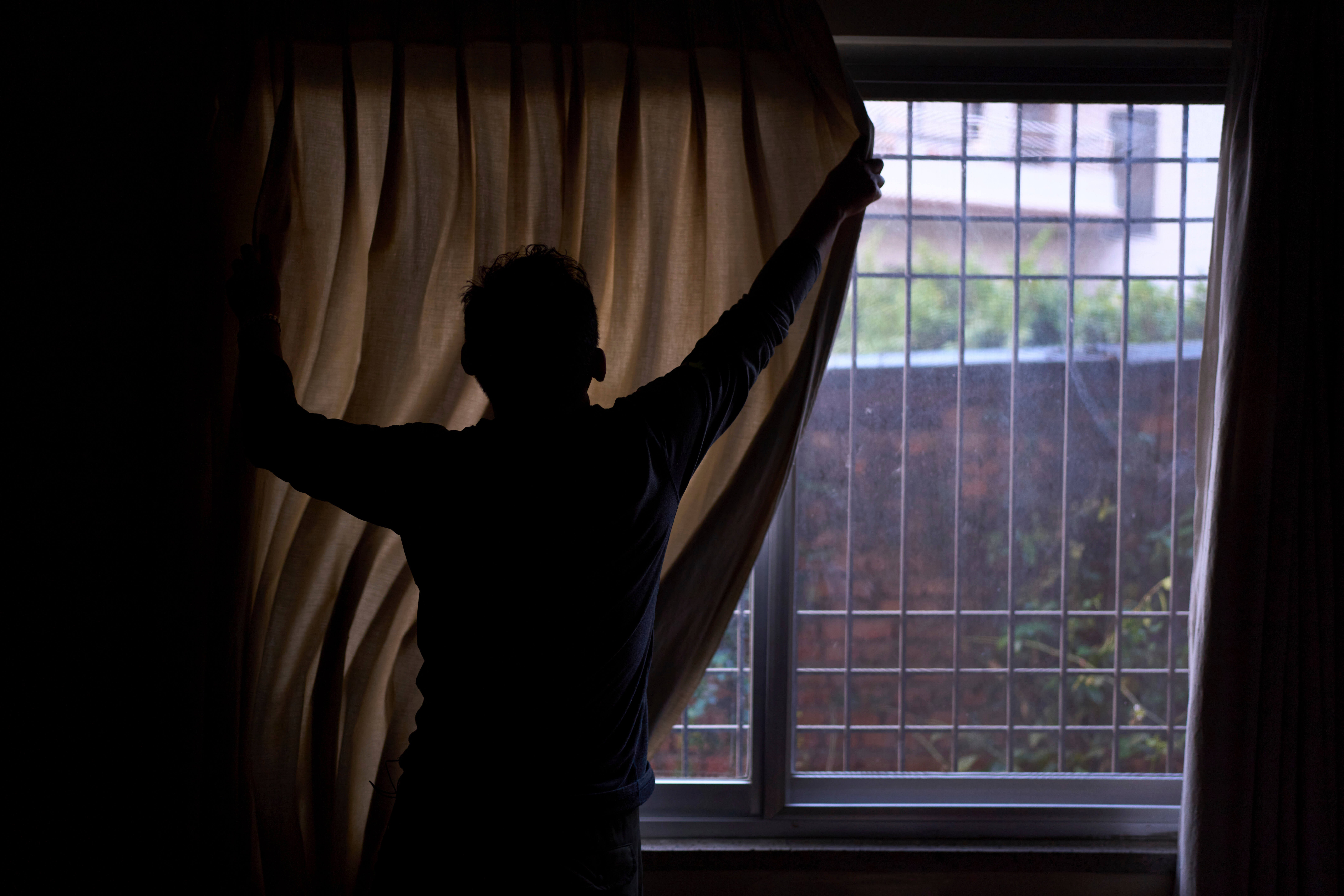 A Tibetan living in exile pulls the curtain before he gives an interview in Kathmandu, Nepal