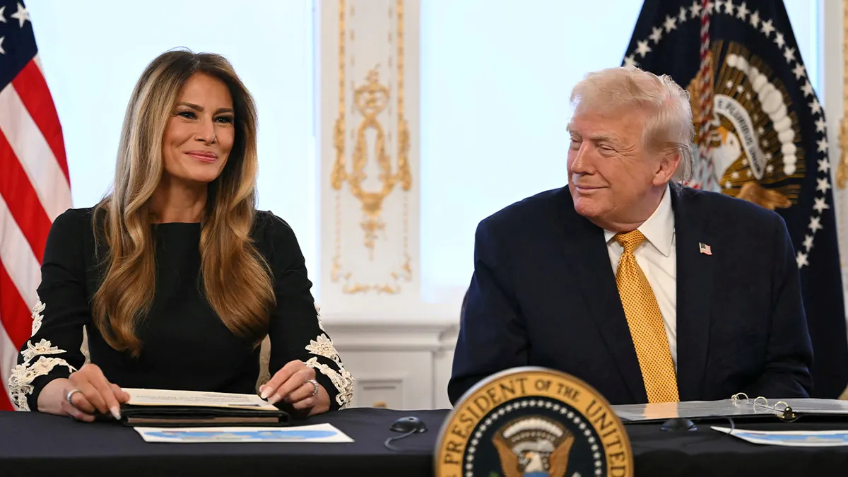Prva dama Melania Trump smiješi se dok sjedi pored predsjednika Donalda Trumpa koji joj se smiješi