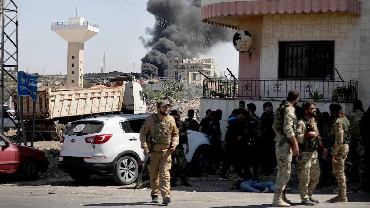 Vojnici se okupljaju u ruralnom području dok se u daljini diže dim od nedavnih nemira.