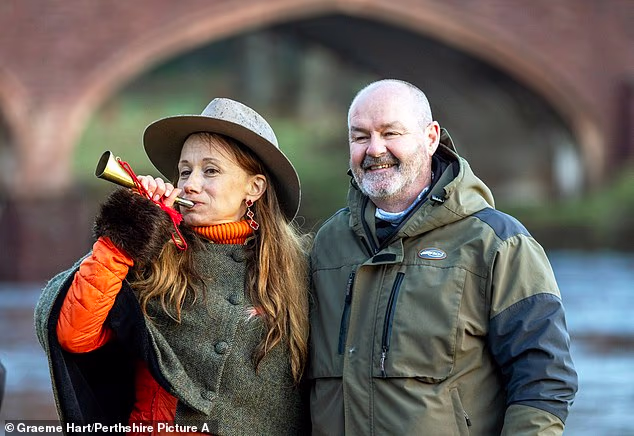 Claire Mercer Nairne iz Tay District Salmon Fisheries trubi u rog proglašavajući sezonu službeno otvorenom, dok Clarke to gleda s odobravanjem