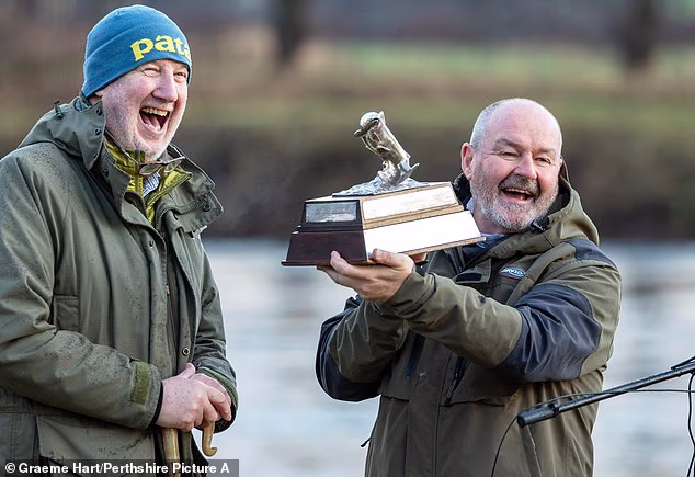 Clarke se šali s Calumom Innesom, predsjednikom Tay Rivers Trusta, dok on drži Malloch Trophy koji se dodjeljuje ribiču koji svake godine ulovi najboljeg lososa
