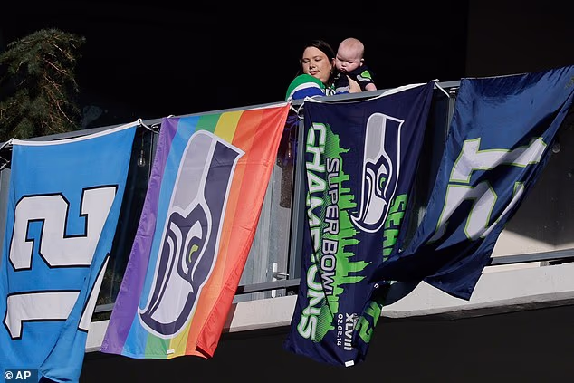 Osoba gleda s balkona dok se navijači Seattle Seahawksa okupljaju uoči parade