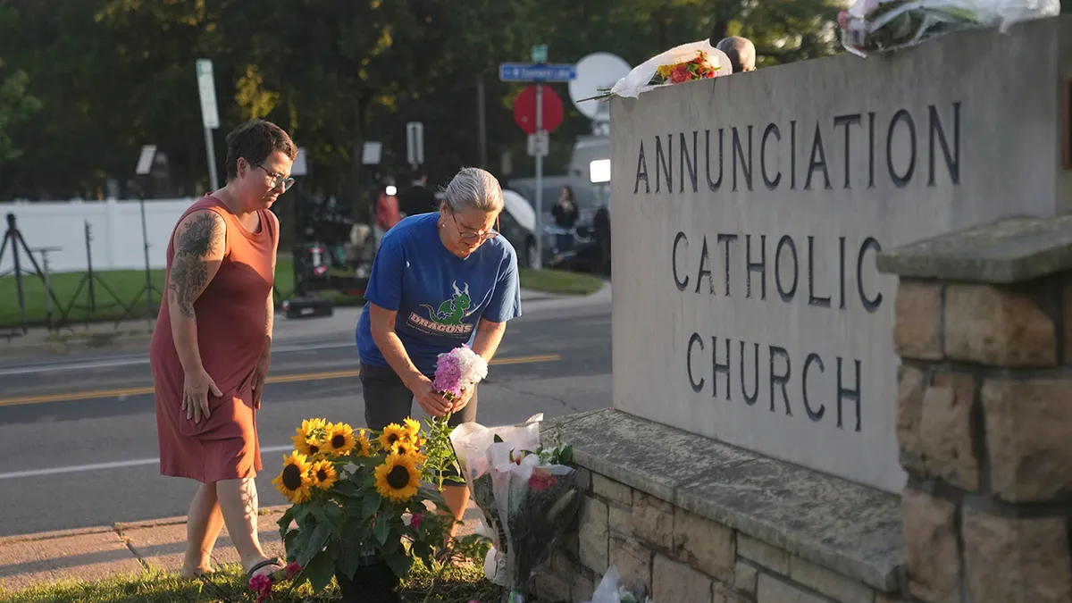 Ožalošćeni posjećuju spomenik postavljen žrtvama masovne školske pucnjave u katoličkoj školskoj crkvi.