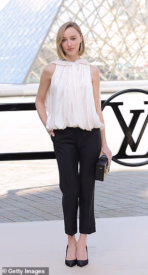 Phoebe Dynevor nosila je bijeli top bez rukava u kombinaciji s crnim hlačama i odgovarajućim štiklama