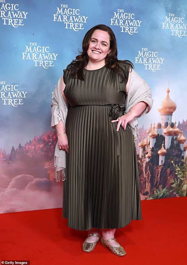 Jessica Gunning, koja glumi Dame Washalot, izgledala je bez napora elegantno u šumskozelenoj plisiranoj haljini, sivom šalu i zlatnim ravnim balvanima