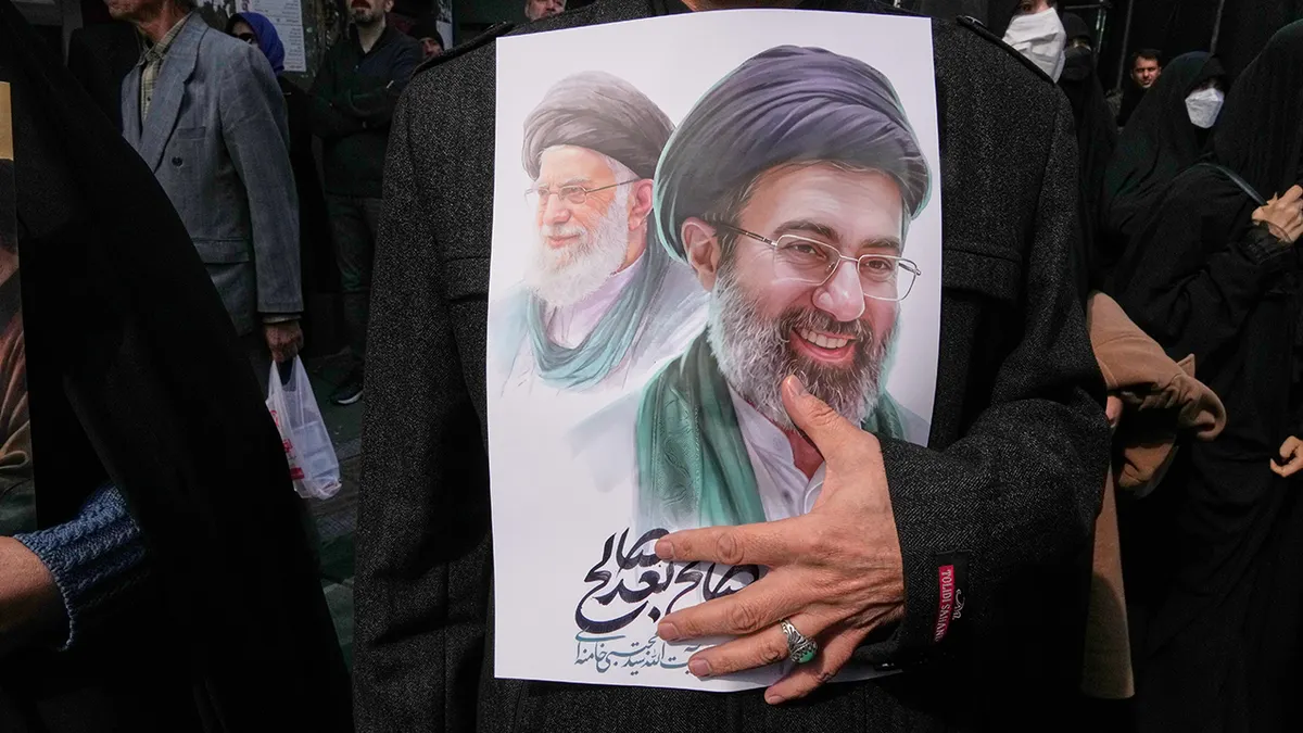 Osoba koja drži poster koji prikazuje ajatolaha Mojtabu Khameneija i ajatolaha Alija Khameneija tijekom pogrebne povorke.