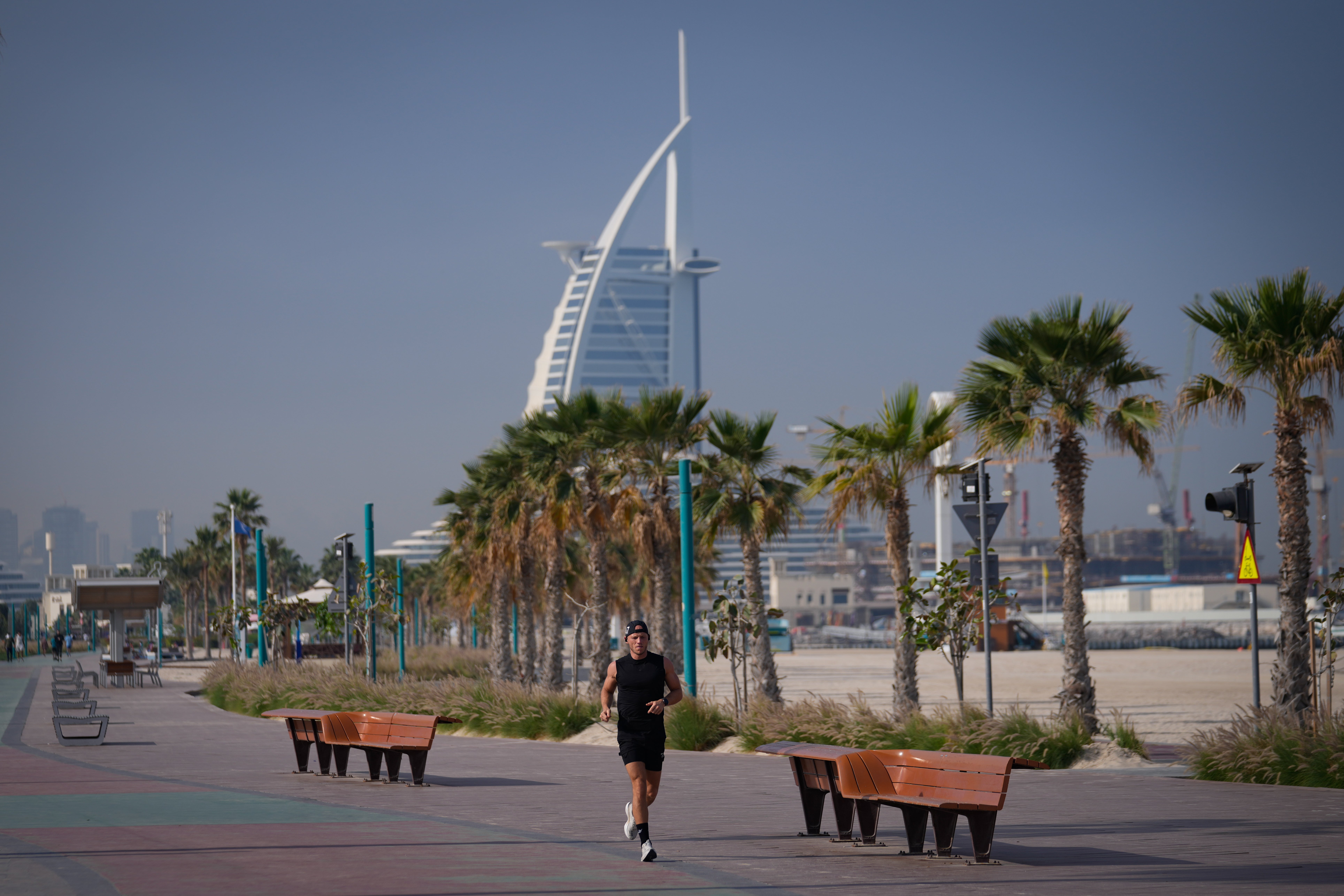 Muškarac džogira plažom s luksuznim hotelom Burj Al Arab viđenim u pozadini u Dubaiju, Ujedinjeni Arapski Emirati, nedjelja, 1. ožujka 2026.