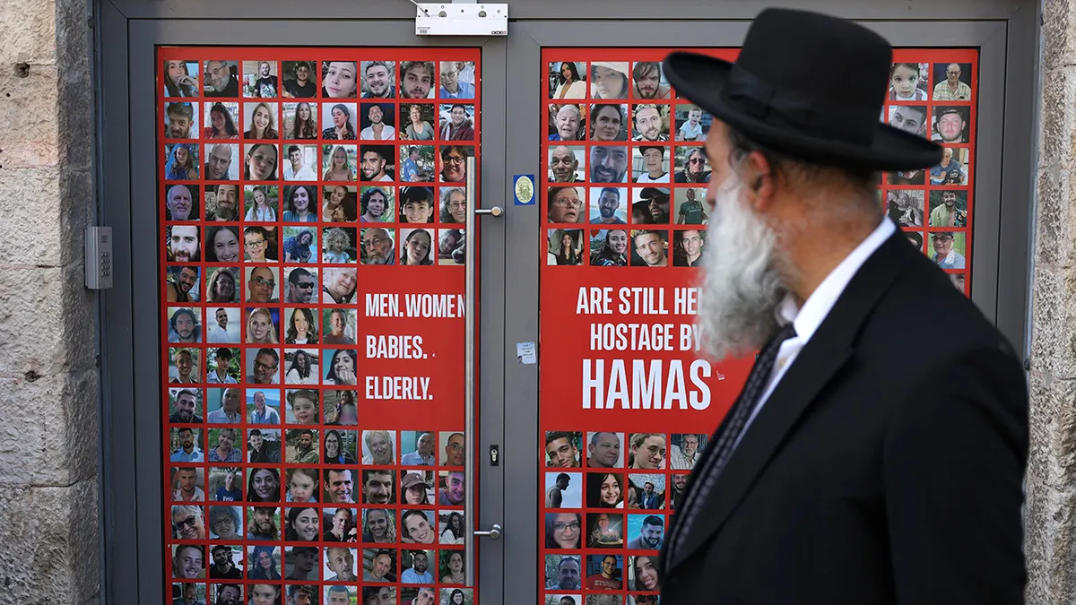 Izraelac prolazi pored transparenta s portretima Izraelaca držanih kao taoci