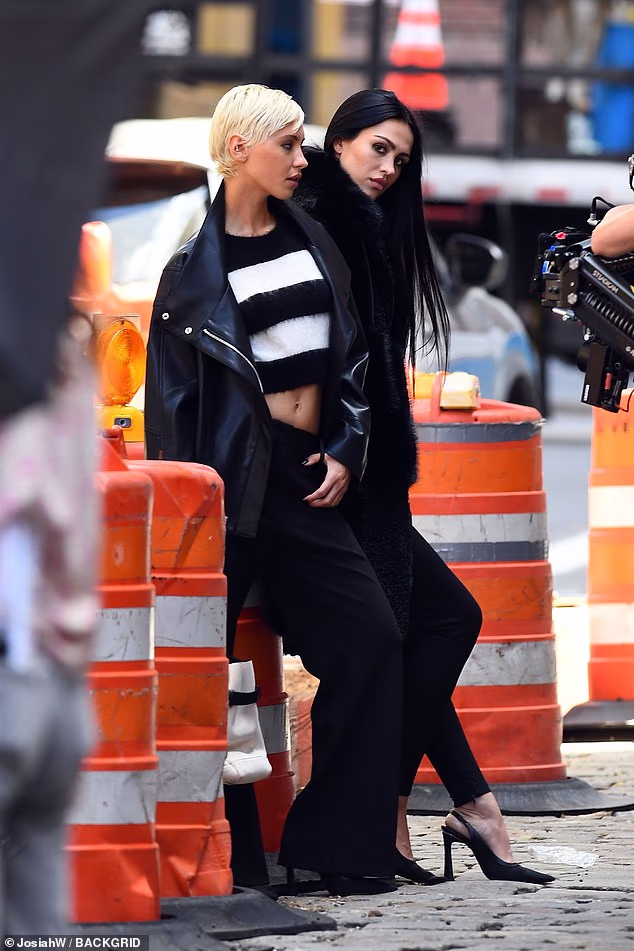 Iris je presložila svoju jaknu preko prugastog džempera koji je iskombinirala s lepršavim hlačama i visokim potpeticama