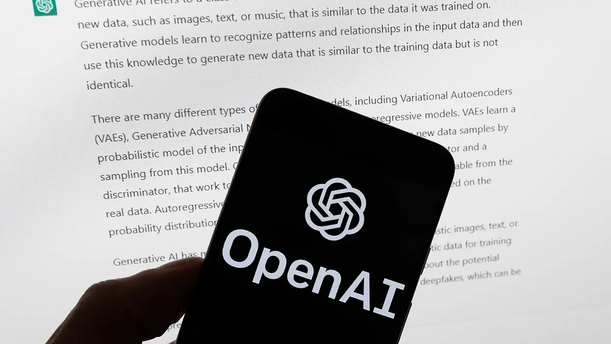 OpenAI logotip prikazan na mobilnom telefonu ispred zaslona računala prikazuje ChatGPT izlaz