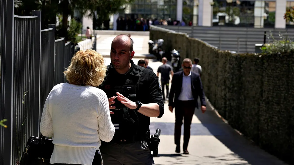 Policajac razgovara sa ženom ispred zgrade suda u Ateni