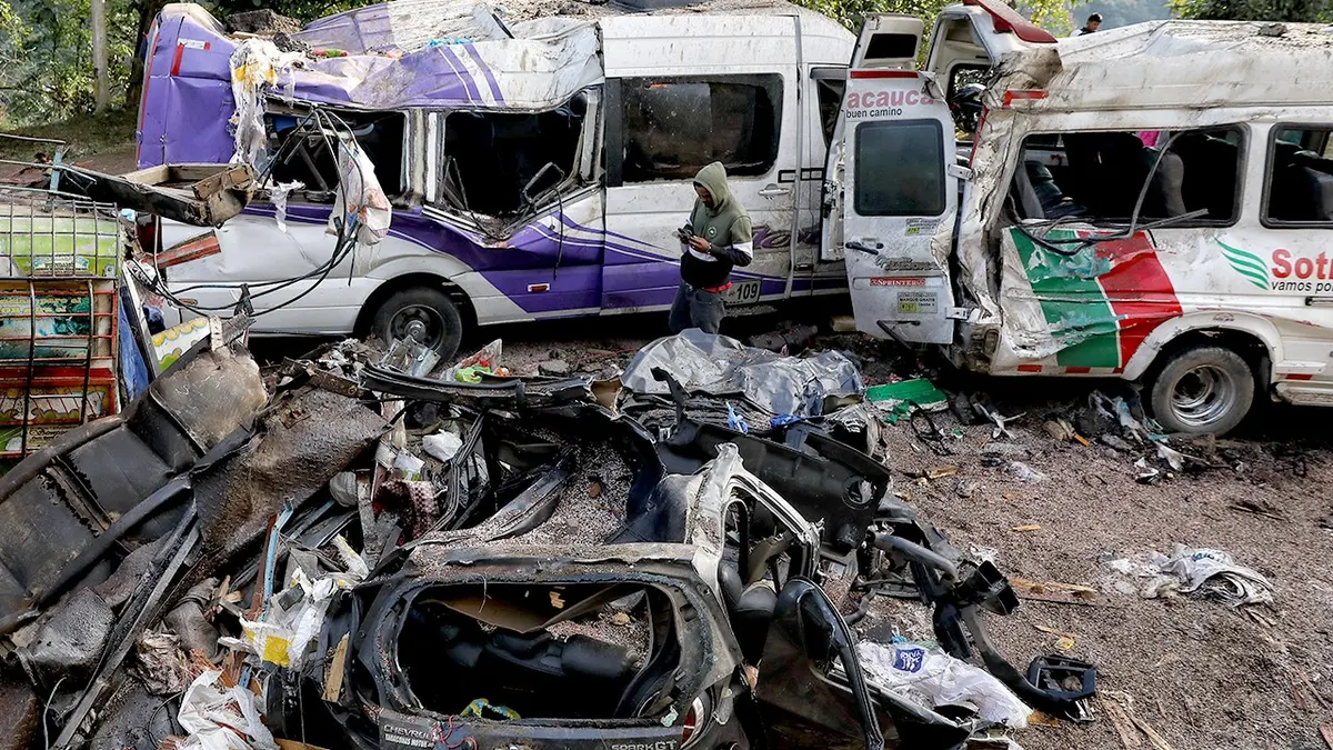 Čovjek stoji usred olupine od eksplozije autobusa.