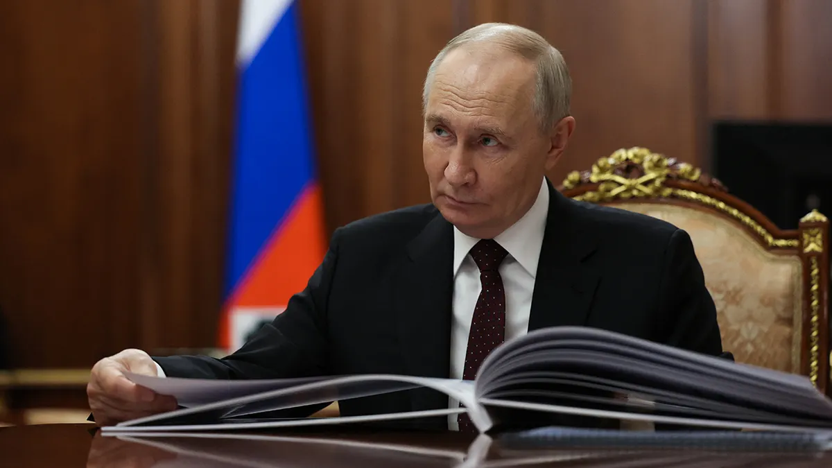 Ruski predsjednik Vladimir Putin sjedi za stolom.