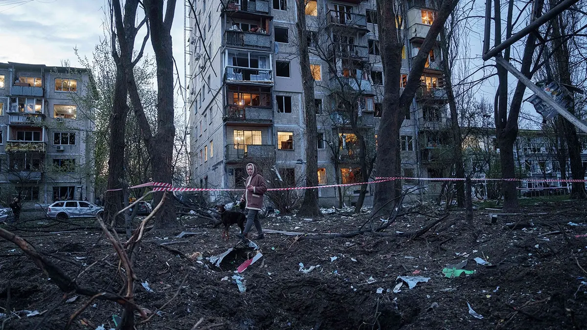 Žena i pas hodaju kroz ruševine.