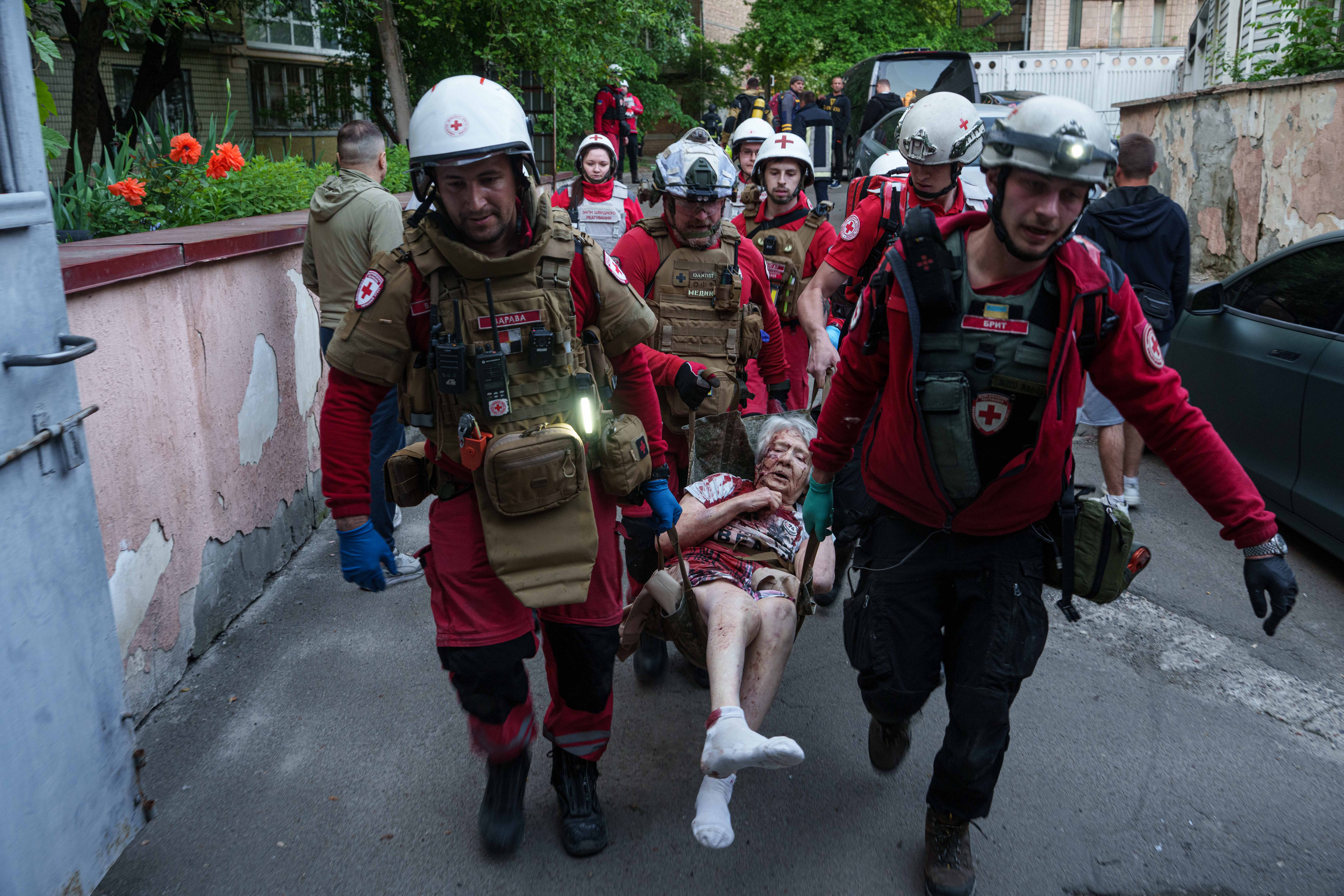 Volonteri Crvenog križa nose ozlijeđenu ženu u vozilo hitne pomoći nakon ruskog napada na stambenu četvrt