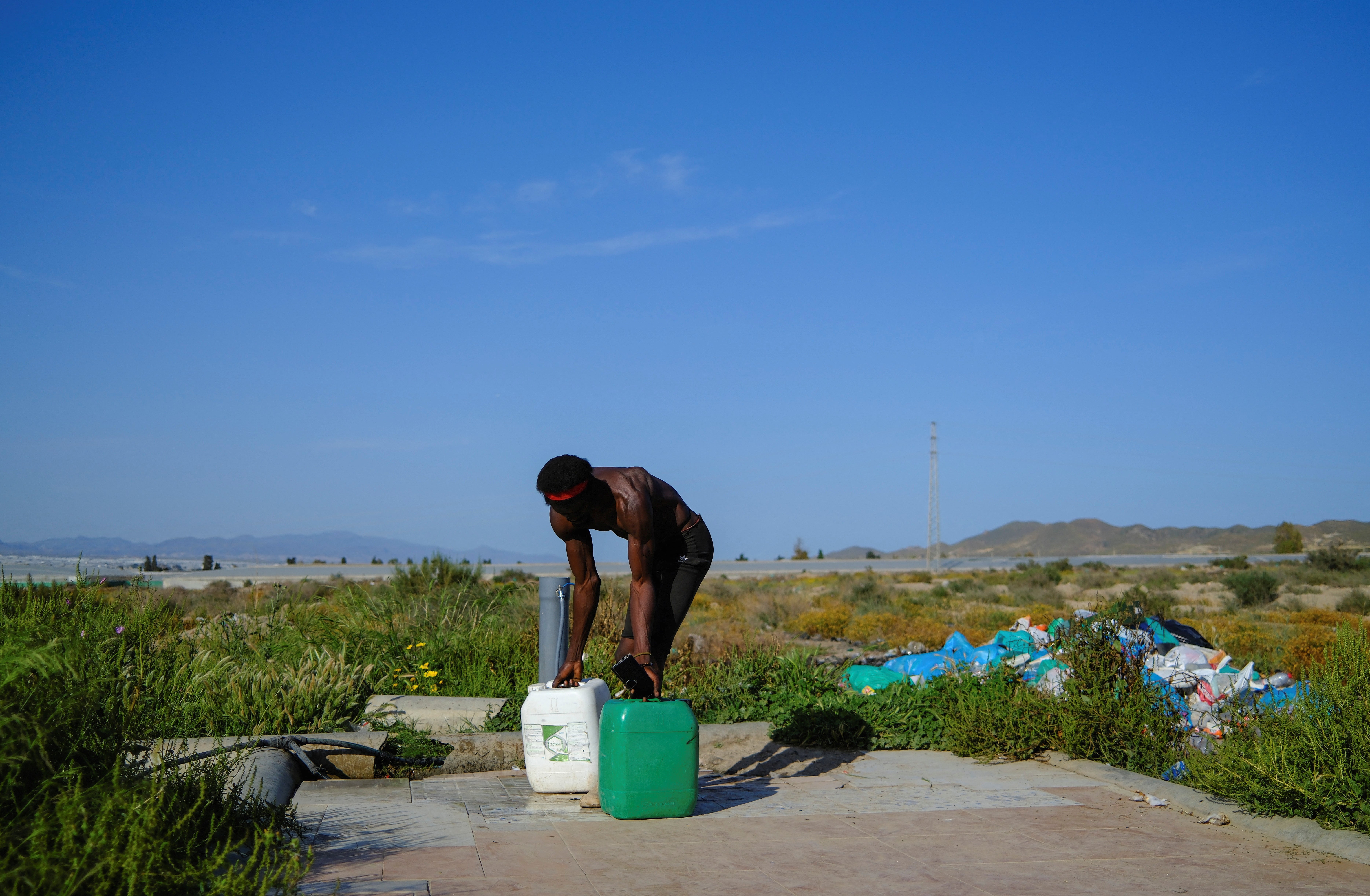 Migrant bez dokumenata iz podsaharske Afrike uzima bačve s vodom u siromašnom gradu.