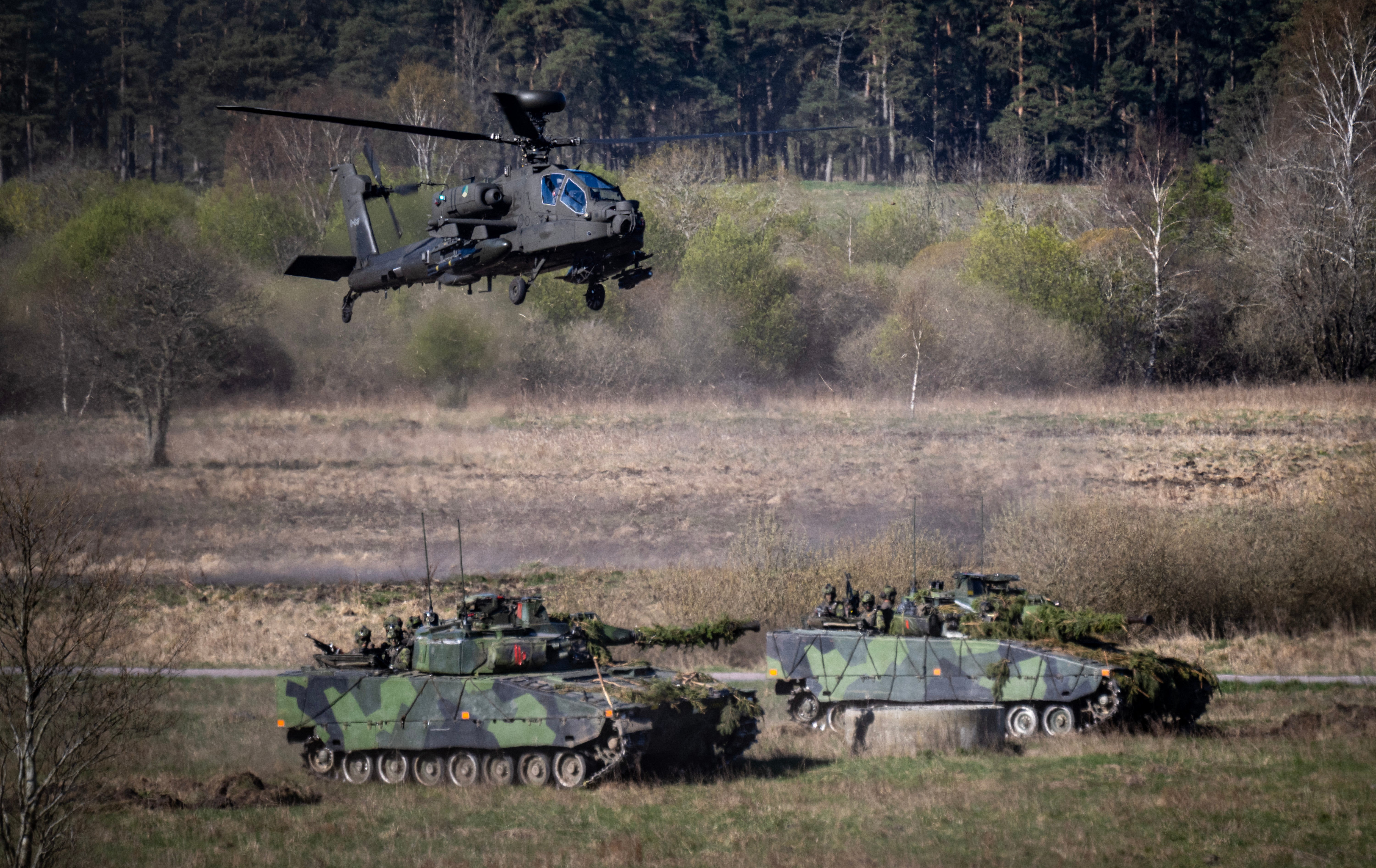 Nizozemski jurišni helikopter Boeing AH-64 Apache nadlijeće 2 švedska oklopna borbena vozila Stridsfordon 90 na gusjenicama dok saveznici NATO-a sudjeluju u borbenom prikazu tijekom dana za novinare za vojnu vježbu Aurora 26 na poligonu Revingehed izvan Lunda u Skaneu, južna Švedska 29. travnja 2026.
