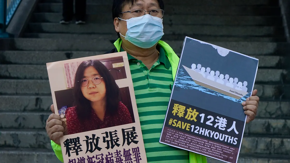 Prodemokratski aktivist koji drži plakate sa slikom kineskog građanina novinara Zhang Zhana ispred ureda za vezu kineske središnje vlade u Hong Kongu
