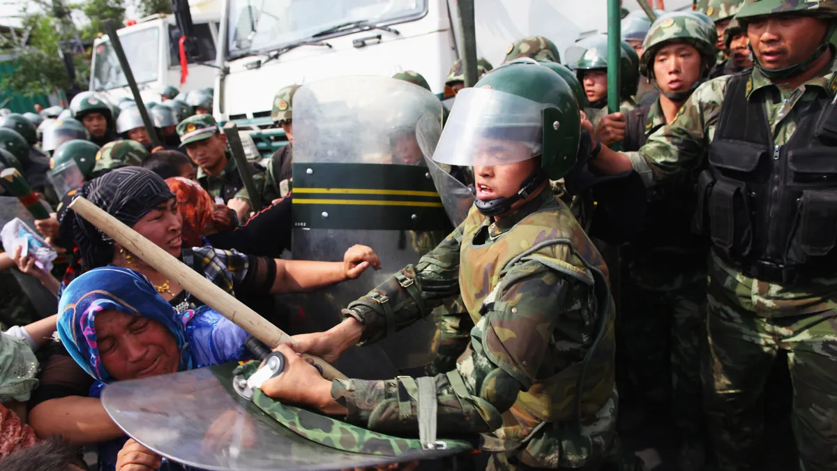 Chinese policemen pushing Uighur women protesting on a street in Urumqi